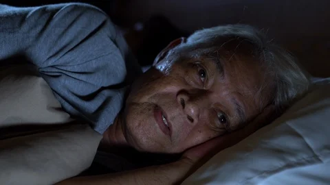 A depressed senior man lying in bed cannot sleep from insomnia . Видео 126889696