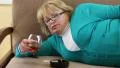 Depressed senior woman lying on the couch and drinking brandy HD Footage