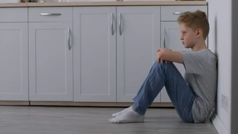 Depressed teen boy with battered face sitting at kitchen, suffering from parents Stock Footage