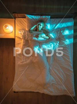 The depressed woman lay on the bed. Evening night time. View from above Stock Photos