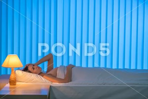 The depressed woman lay on the bed. Evening night time Stock Photos
