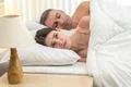 The depressed woman lay near man on the bed Photo