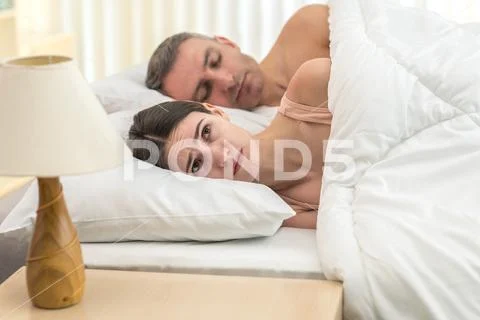 The depressed woman lay near man on the bed Stock Photos