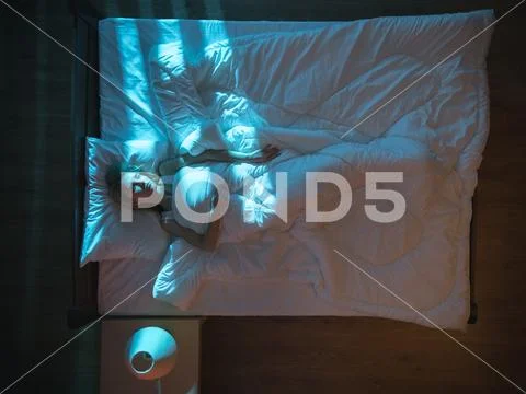 The depressed woman lie on the bed. Evening night time. View from above Stock Photos