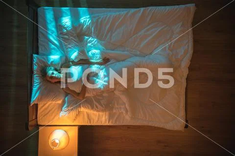 The depressed woman lie on the bed. Evening night time. View from above Stock Photos