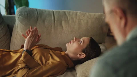 Depressed woman sharing her problems with psychotherapist while lying on sofa Stock Footage 332985822