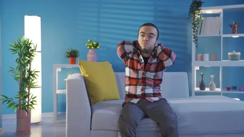 Depressed young man with dwarfism thinking alone at home.  Stock Footage 230971635