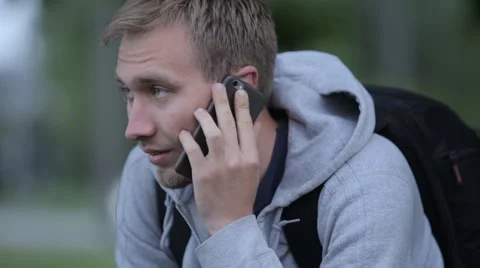 Depressed young man nervously talking on cell phone Stock Footage 63909910
