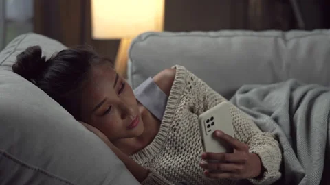 Depressed young woman is crying while lying in the couch checking smartphone. Stock Footage 196963897