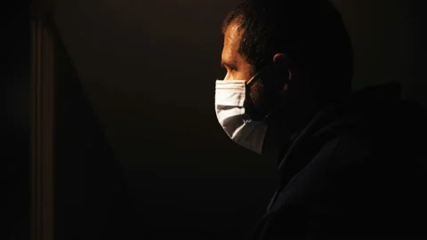 Depression due to the covid - man in the dark pulls down his mask and looks away Video stock 142913392