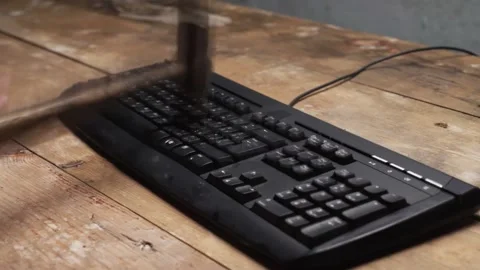Depression at work. A fired worker smashes a computer keyboard with a hammer. 動画素材 136849940