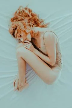 Depressive redhead model laying on bed Stock Photos