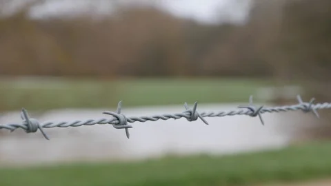 Depth of field shot of a barbed wire fence with a river in the background Stock Footage 122204692