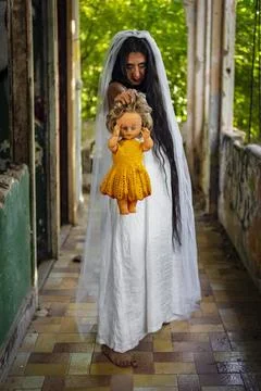 Deranged bride with a doll in abandoned place Inspired by the traditional Stock Photos