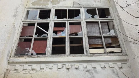 Derelict building with a vandalized broken window, shattered glass, and boarded 動画素材 329747700