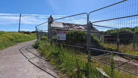 Derelict Welsh seafront cottage surrounded by security wired fencing and Video stock 339089603