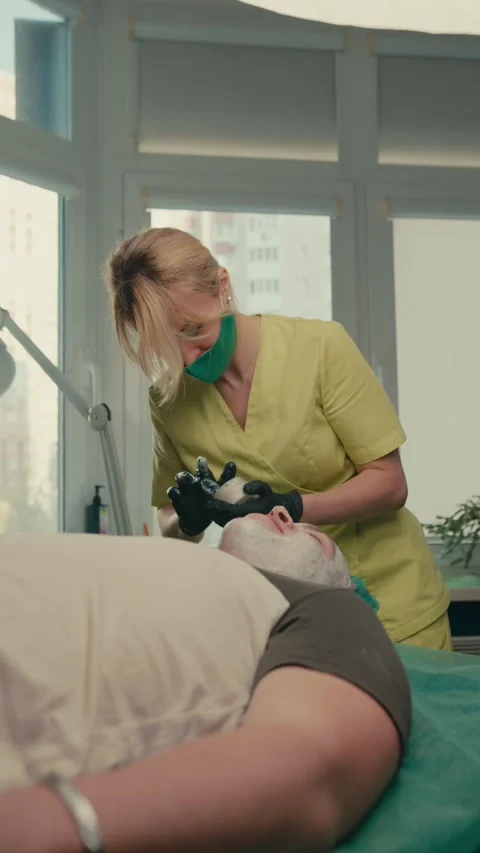The dermatologist cleanses the patient's problem skin with lotion  Stock Footage 286217196