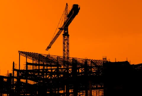 Derrick cranes in construction site at sunset time Stock Photos