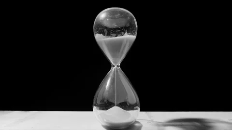 Desaturated arcing shot of sand falling in hourglass, time running out concept Stock Footage 297187725