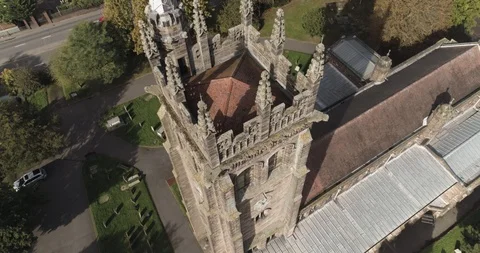 Descending aerial shot shows structures on top of English church Stock Footage 102400376
