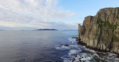 Descending aerial view of cliffs and sea waves breaking at them. Summer day Stock Footage 107652102