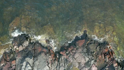 Descending aerial view of waves hitting a rocky beach Stock Footage 138174772