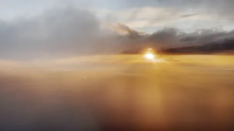 Descending through clouds at sunset over water Stock Footage 168597650
