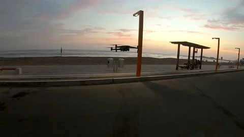 Descent of a drone on a sidewalk at sunset on a beach. Video stock 164003400