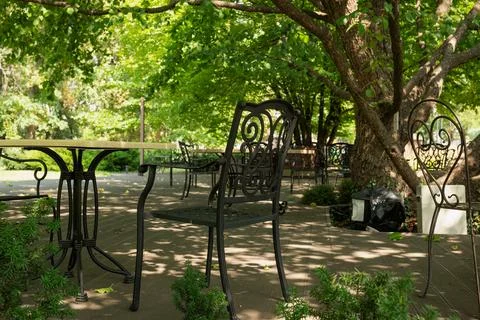 Description: Empty outdoor cafe terrace with wrought iron chairs and tables s Stock Photos
