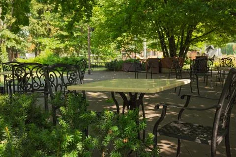 Description: Empty outdoor cafe terrace with wrought iron chairs and tables.. Stock Photos