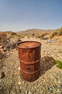 Desert with detail of large orange rusted mining barrel Stock-Fotos
