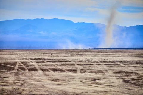 Desert Dust Devil and Mountains with Tire Tracks at Eye Level Perspective Stock Photos