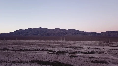 Desert flying towards power lines with mountains in background during sunset Stock Footage 81575003