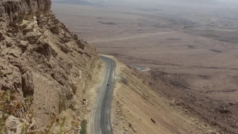 Desert Highway Winding Down Steep Cliffside Overlooking Expansive Arid Land.. Stock Footage 302312183