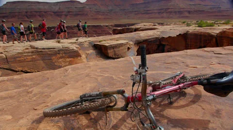Desert Mountain Biking Riders Walking across Arch Video stock 25211604