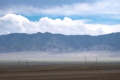 Desert mountain landscape under a cloudy sky with empty road and power lines. 스톡 사진