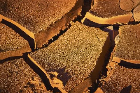 Desert Mud Crack Texture Close Up with Dramatic Light and Parched Earth Stock Photos