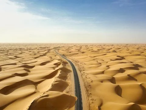 Desert road surrounded by sand dunes Stock Photos