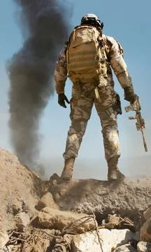 Desert soldier back posing on stone mountain. Stock Photos