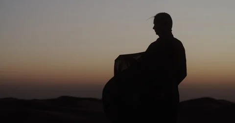 In desert at sunset, woman in the wind develops traditional Abaya dress Video stock 126577325