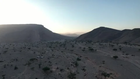 Desert Valley at Dawn with Distant Mountains and Small Camp Stock Footage 336025309