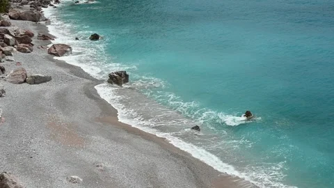 Deserted beach with rocks and blue sea waves crashing Vídeo Stock 241839947