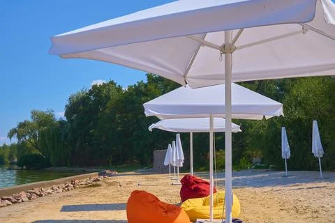 Deserted empty sandy beach with open umbrellas by the sea,lake,river Stock Photos