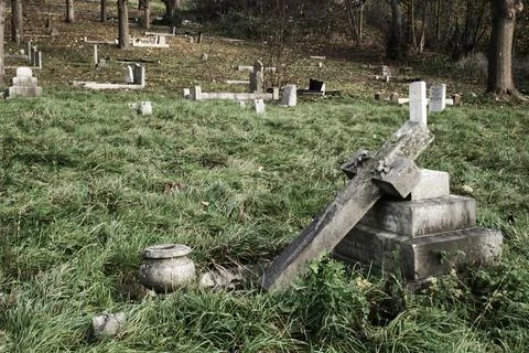 Deserted overgrown graveyard with grey stone headstones Stock Photos