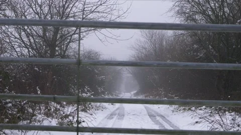 Deserted road after snowfall in winter through view of gate Stock Footage 159439202
