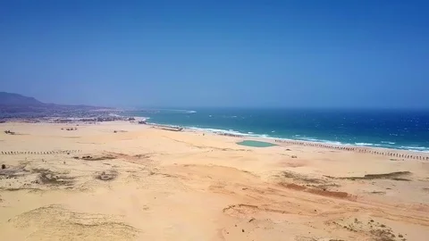 Deserted sandy coast by ocean under clear blue sky Stock Footage 100188972