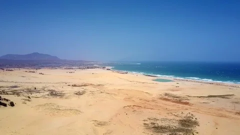 Deserted sandy coast by ocean under clear blue sky Stock Footage 100248184