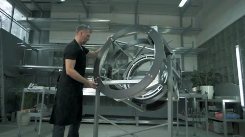 Design engineer assembles a metal frame in an assembly shop in a factory Stock Footage 179699515