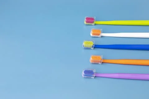Design Flat Lay Multicolor Toothbrushes on Blue Background, Copy Space. Oral Stock Photos