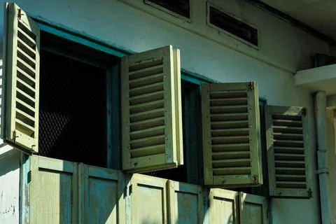 The design of an open window from an old, dull teal-colored house. Stock Photos